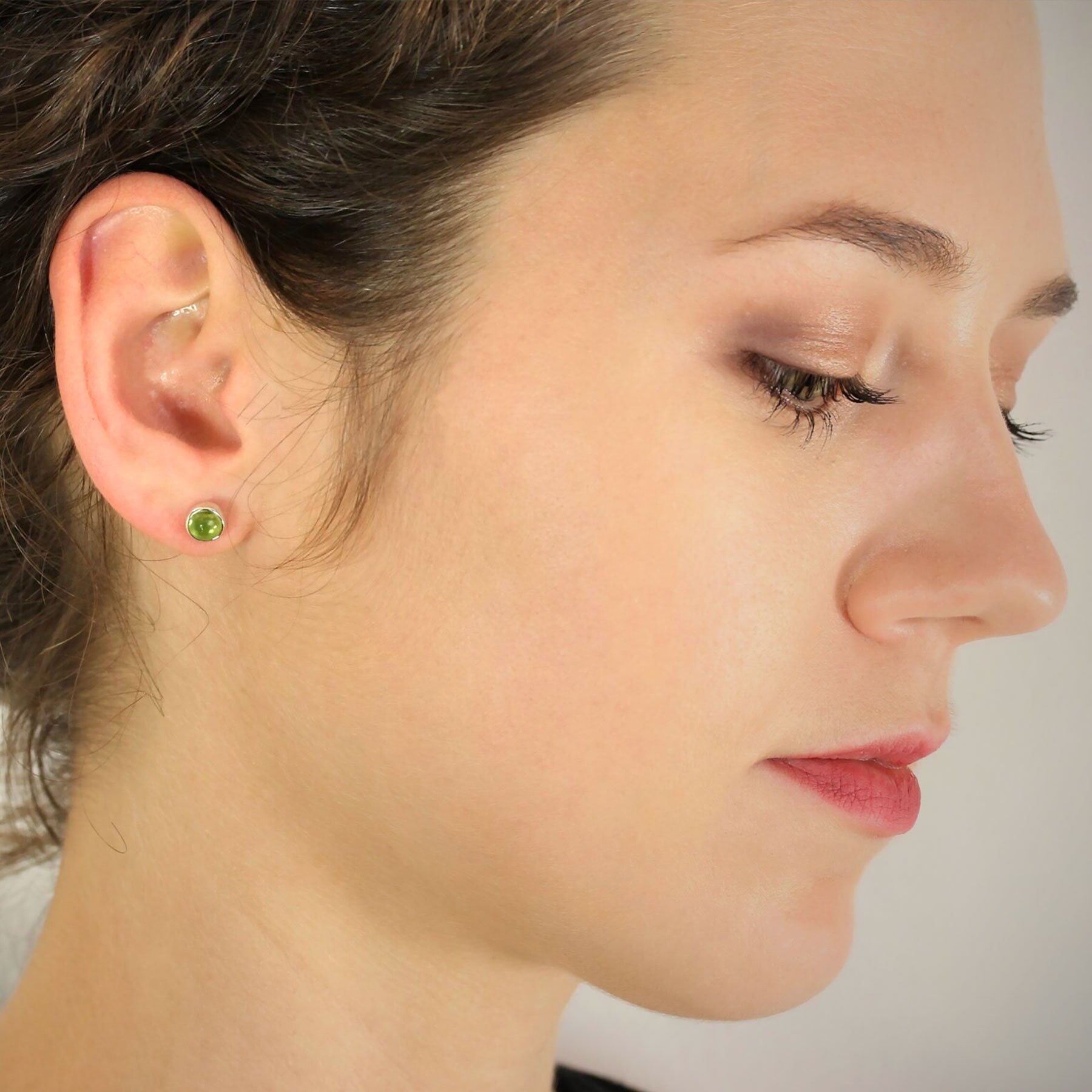 August birthstone earrings with peridot in silver on model